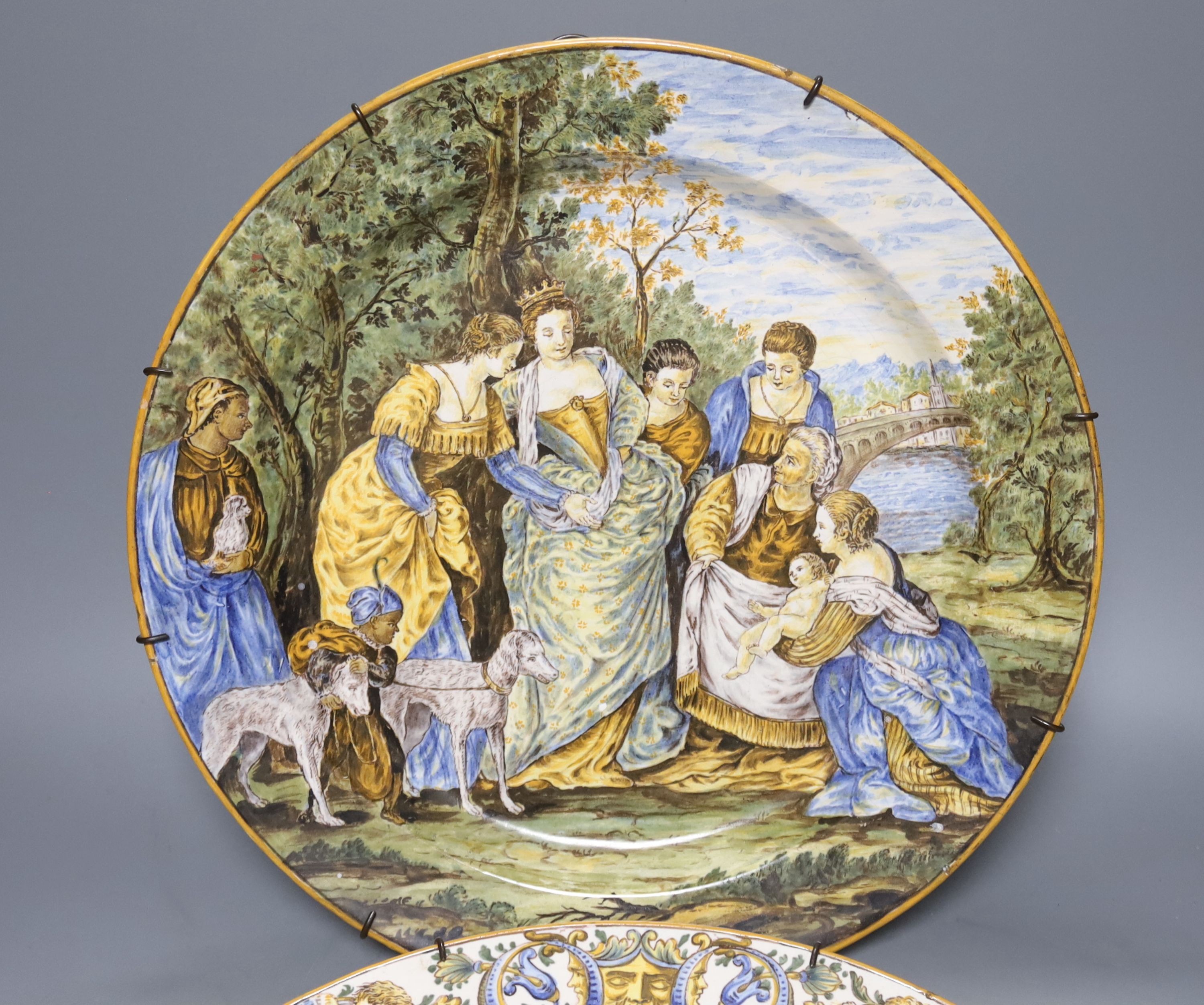 Two Italian Urbano style chargers ‘The Finding of Moses’ and figures by a fire, 37 cms diameter.